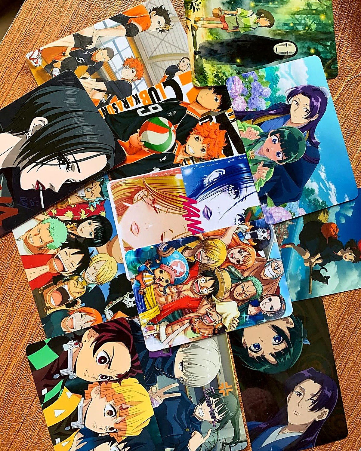 Vários photocards de anime impressos espalhados sobre a mesa